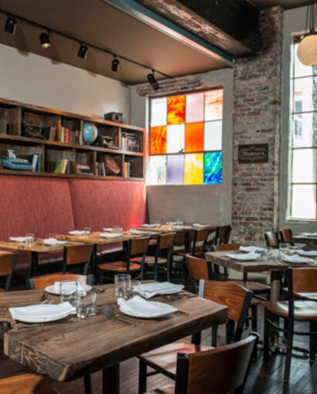 Tables, bookshelves, brick walls, and a tall window in Bluebeard’s dining room.