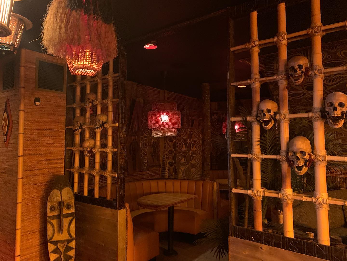 A booth surrounded by bamboo screens, hanging lamps, and decorative objects inside Inferno Room.